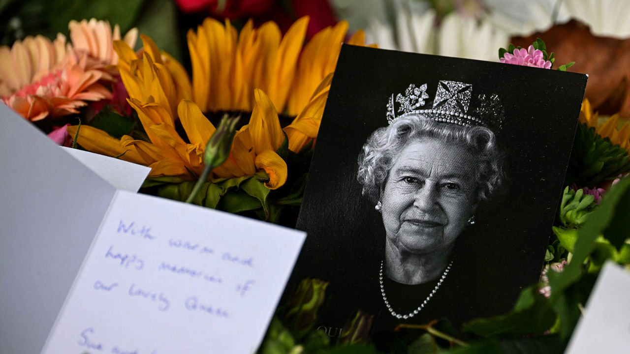 A portrait of late Queen Elizabeth II is pictured among flowers and tributes left in Green Park in London on September 18, 2022. Credit: AFP Photo