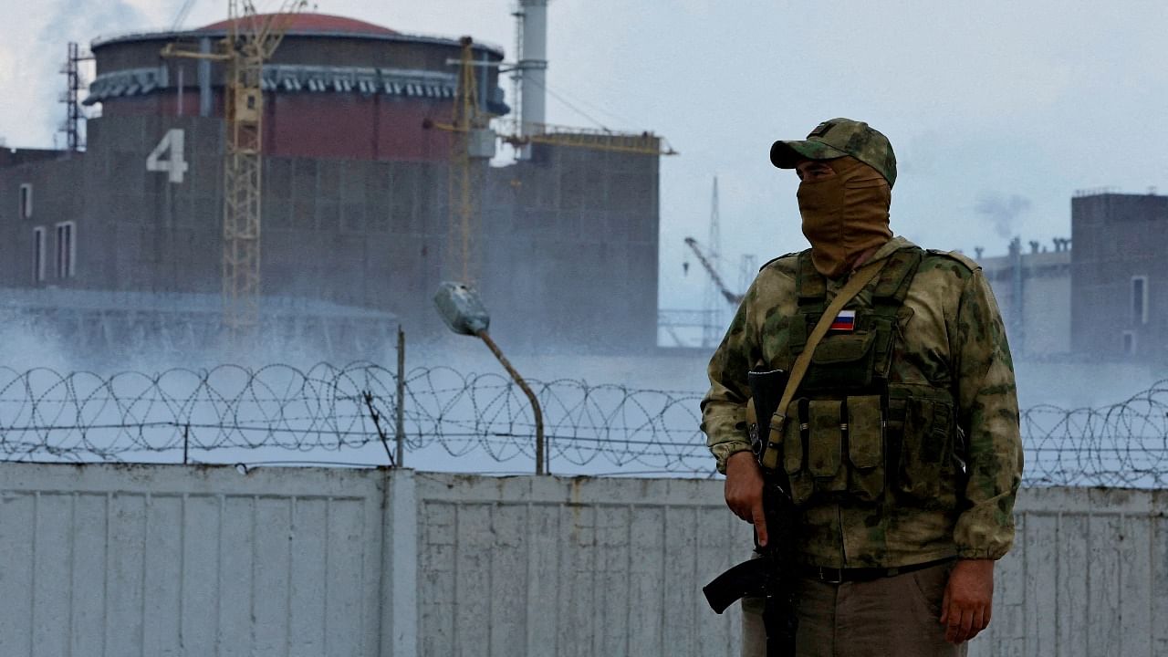 A serviceman with a Russian flag on his uniform stands guard near the Zaporizhzhia Nuclear Power Plant in the course of Ukraine-Russia conflict outside the Russian-controlled city of Enerhodar in the Zaporizhzhia region. Credit: Reuters Photo