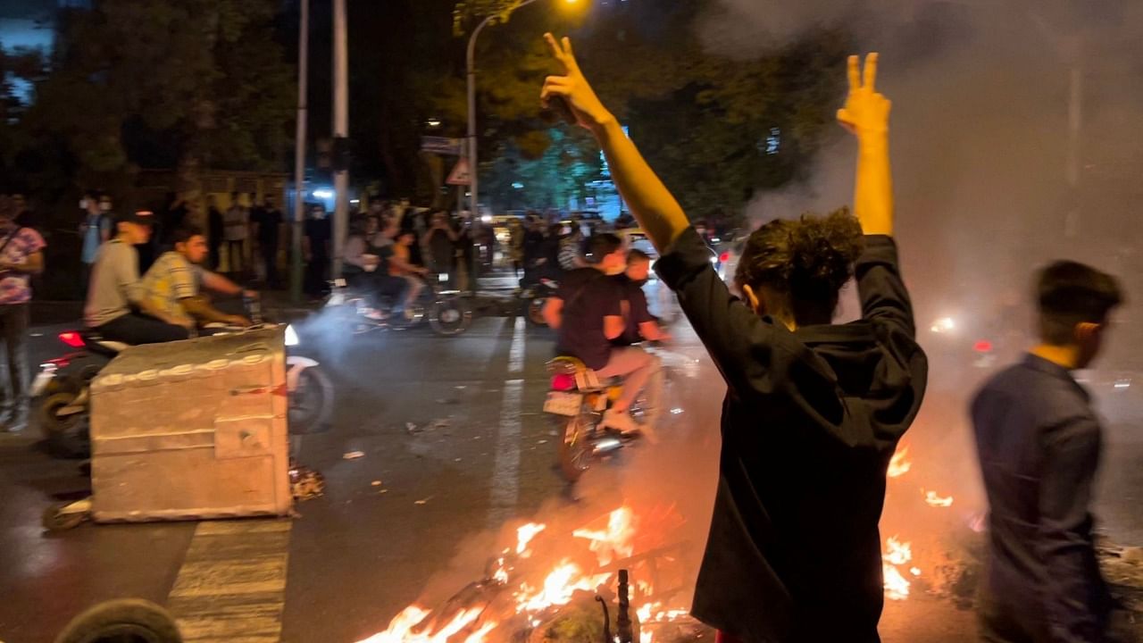 A demonstrator raises his arms and makes the victory sign during a protest for Mahsa Amini, a woman who died after being arrested by the Islamic republic's "morality police". Credit: AFP Photo