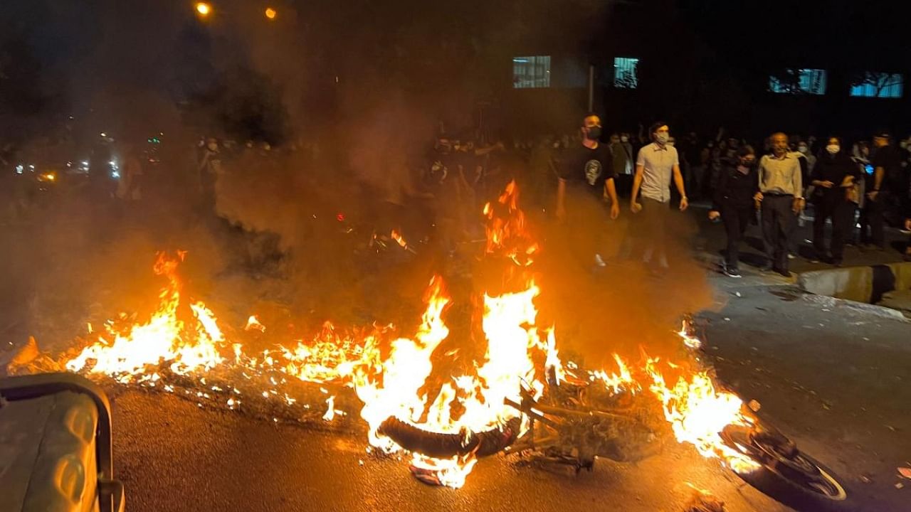 Demonstrators gather near a motorbike on fire during a protest for Mahsa Amini, a woman who died after being arrested by the Islamic republic's "morality police", in Tehran on September 19, 2022. - Fresh protests broke out on September 19 in Iran over the death of a young woman who had been arrested by the 'morality police' that enforces a strict dress code, local media reported. Credit: AFP Photo