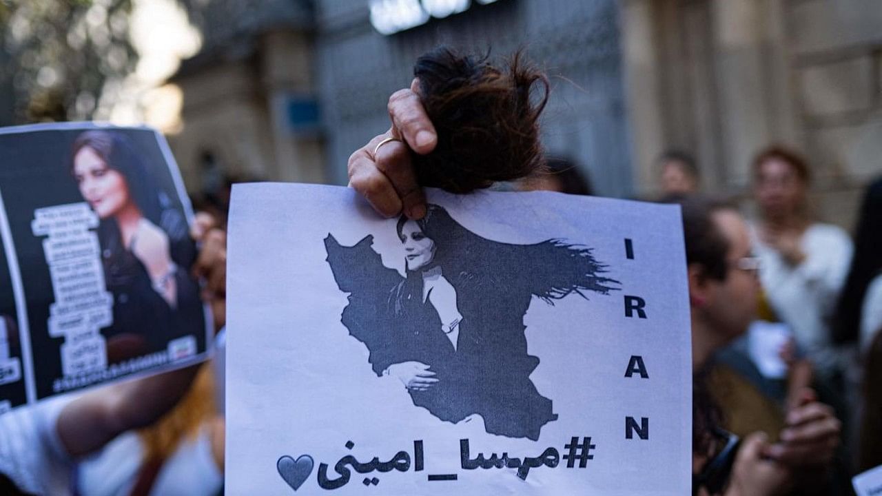 An Iranian woman living in Turkey, holds a ball of her cut hair and a poster of Mahsa Amini, during a protest outside the Iranian consulate in Istanbul on September 21, 2022, following the death of an Iranian Amini after her arrest by the country's morality police in Tehran. Credit: AFP Photo