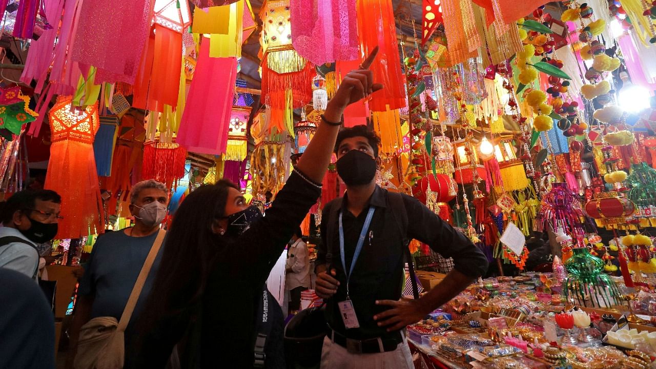 People wearing face masks shop for lanterns at a market ahead of Diwali. Credit: Reuters Photo