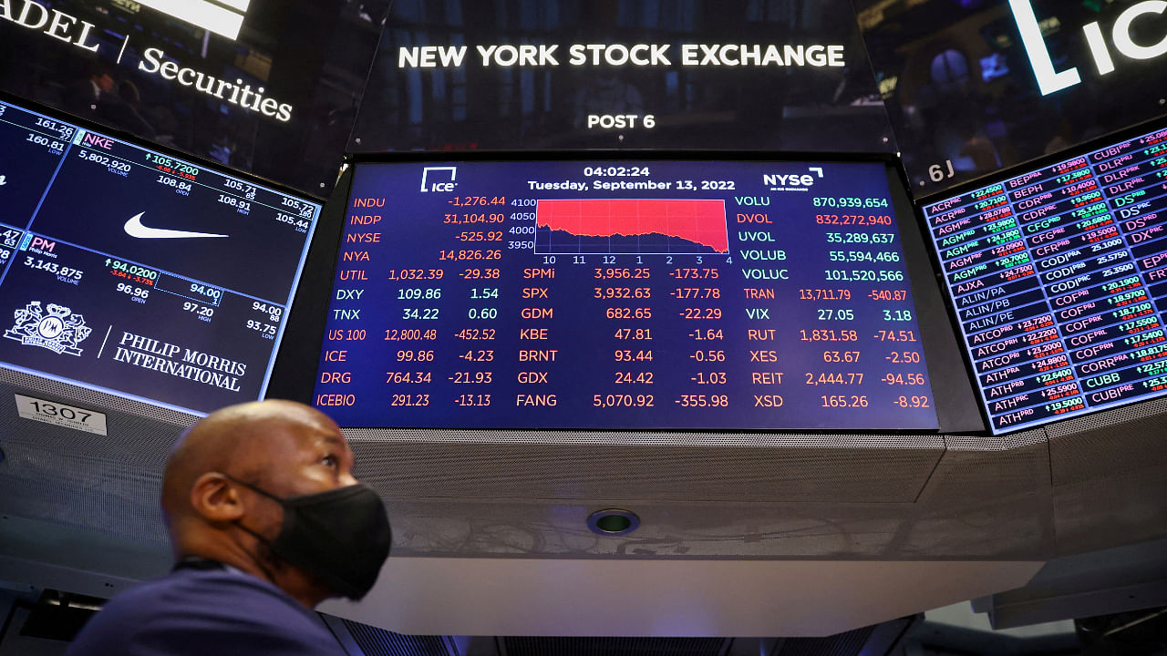 A trader stands beneath a screen on the trading floor displaying the Dow Jones Industrial Average at the New York Stock Exchange (NYSE) in Manhattan, New York City, US, September 13, 2022. Credit: Reuters File Photo
