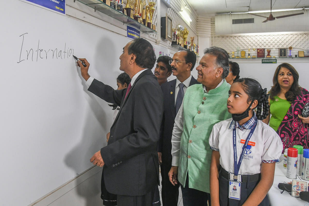 N Parthasarathi writes on a canvas at the Rotary House of Friendship, Lavelle Road. Rotary Club of Bangalore Secretary M C Dinesh, and President Sanjay Udani (in green), are also seen. DH Photo BY S K Dinesh
