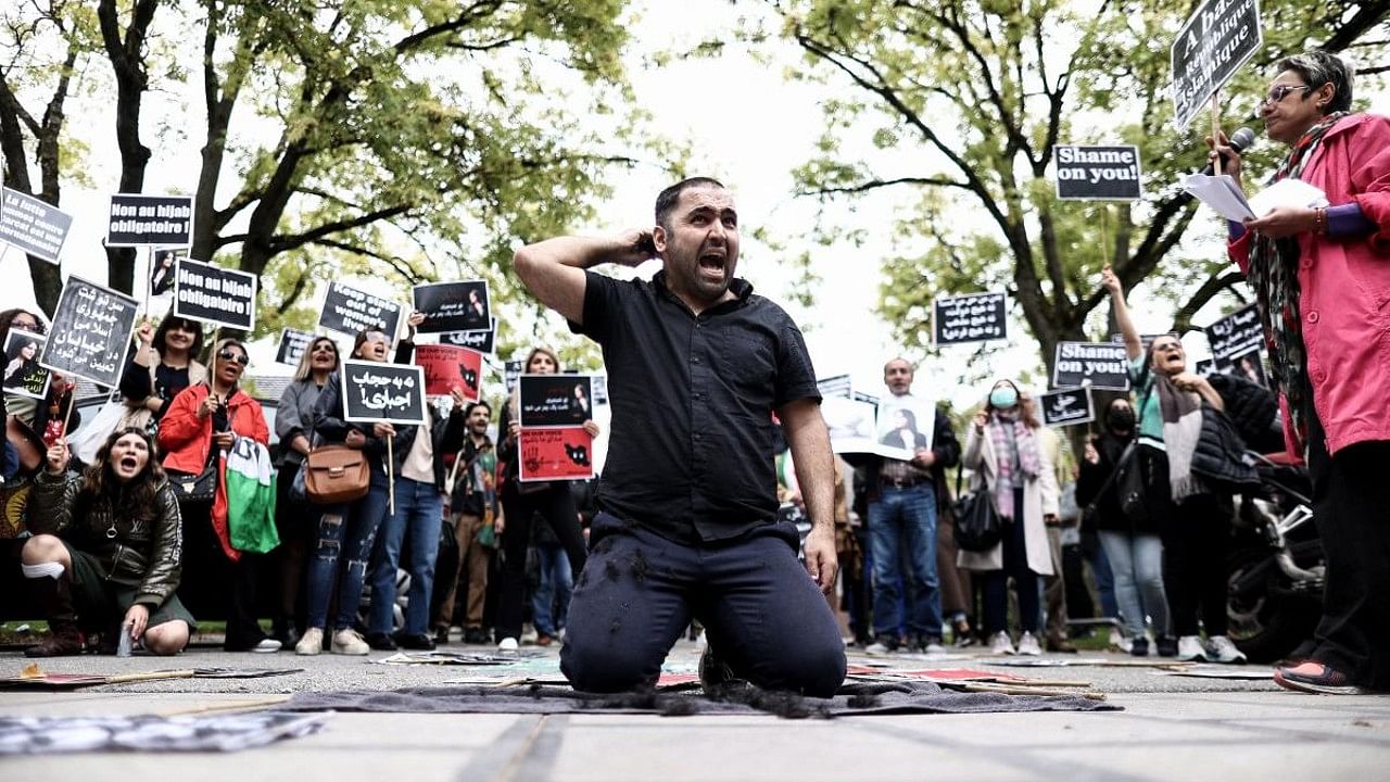 A man cuts his hair during a demonstration in support of Mahsa Amini in front of the Iranian embassy in Brussels. Credit: AFP Photo