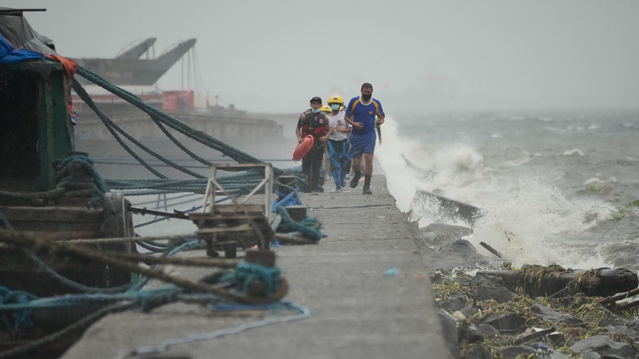 Rescuers run as they check residents living at the seaside slum district of Tondo while Typhoon Noru approaches Manila, Philippines, Sunday, Sept. 25, 2022. Credit: AP/PTI Photo