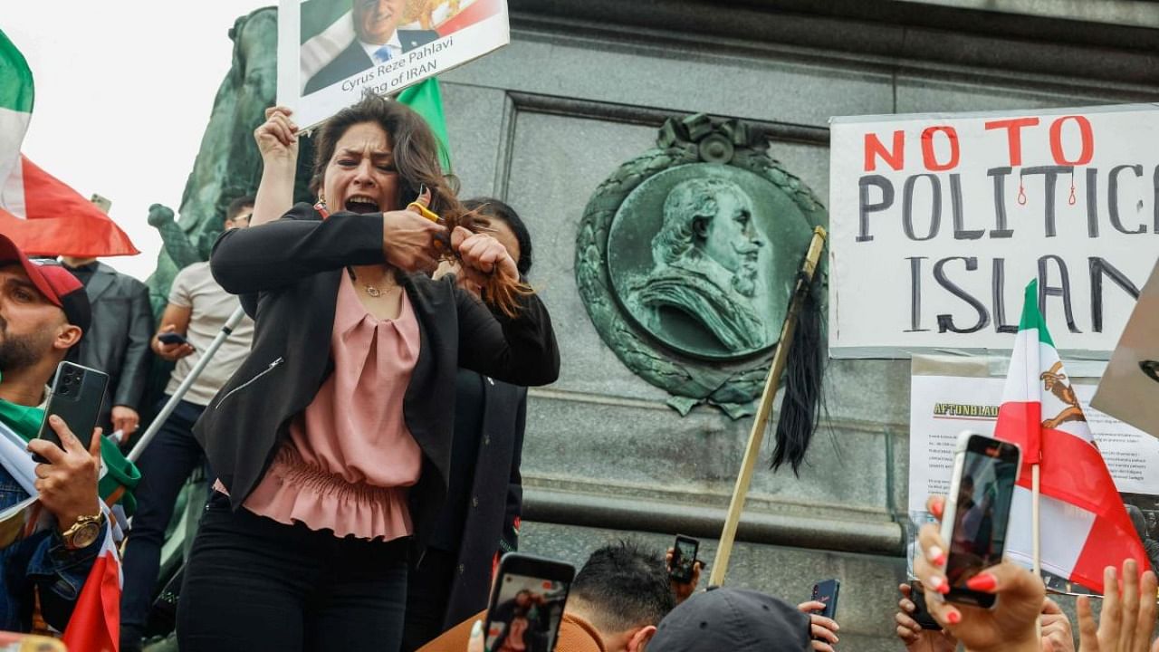 A woman cuts her hair during a demonstration in Sergels Torg in Stockholm, Sweden on September 24, 2022, following the death of an Iranian woman after her arrest by the country's morality police in Tehran. Credit: AFP Photo