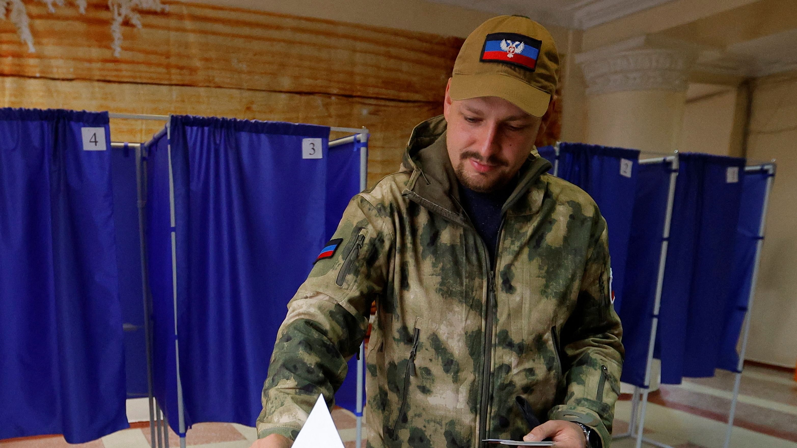 A service member of the self-proclaimed Donetsk People's Republic (DPR) casts his ballot at a polling station during a referendum on the joining of DPR to Russia. Credit: Reuters Photo