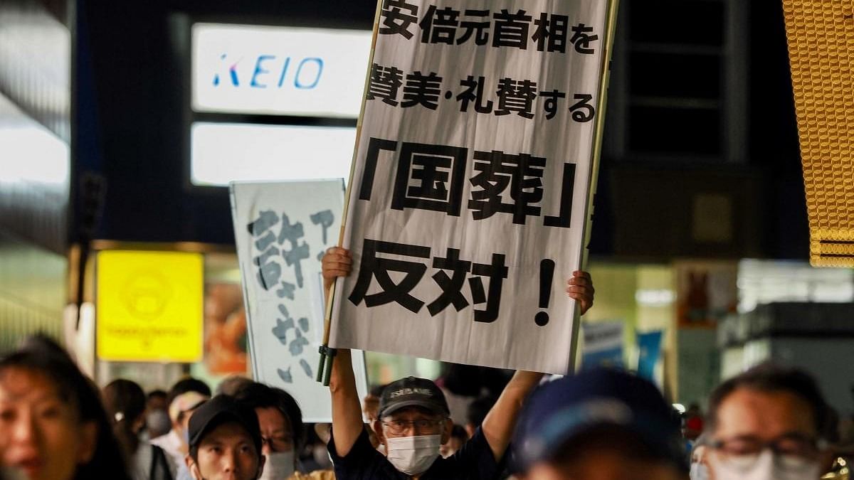 A man holds up a banner to protest against the state funeral for late prime minister Shinzo Abe as people gather to demonstrate in Tokyo. Credit: AFP Photo