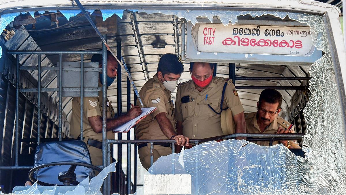 Police personnel take stock of the damages done to a Kerala State Road Transport Corporation bus after some miscreants threw stones on it, during the 'hartal' called by Popular Front of India (PFI). Credit: PTI Photo