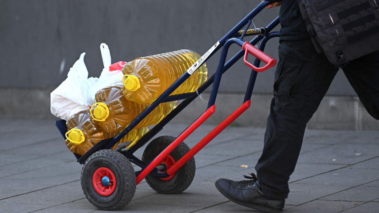 A man transports containers with sunflower oil at the main railway station in Cologne, western Germany on March 22, 2022. Credit: AFP File Photo