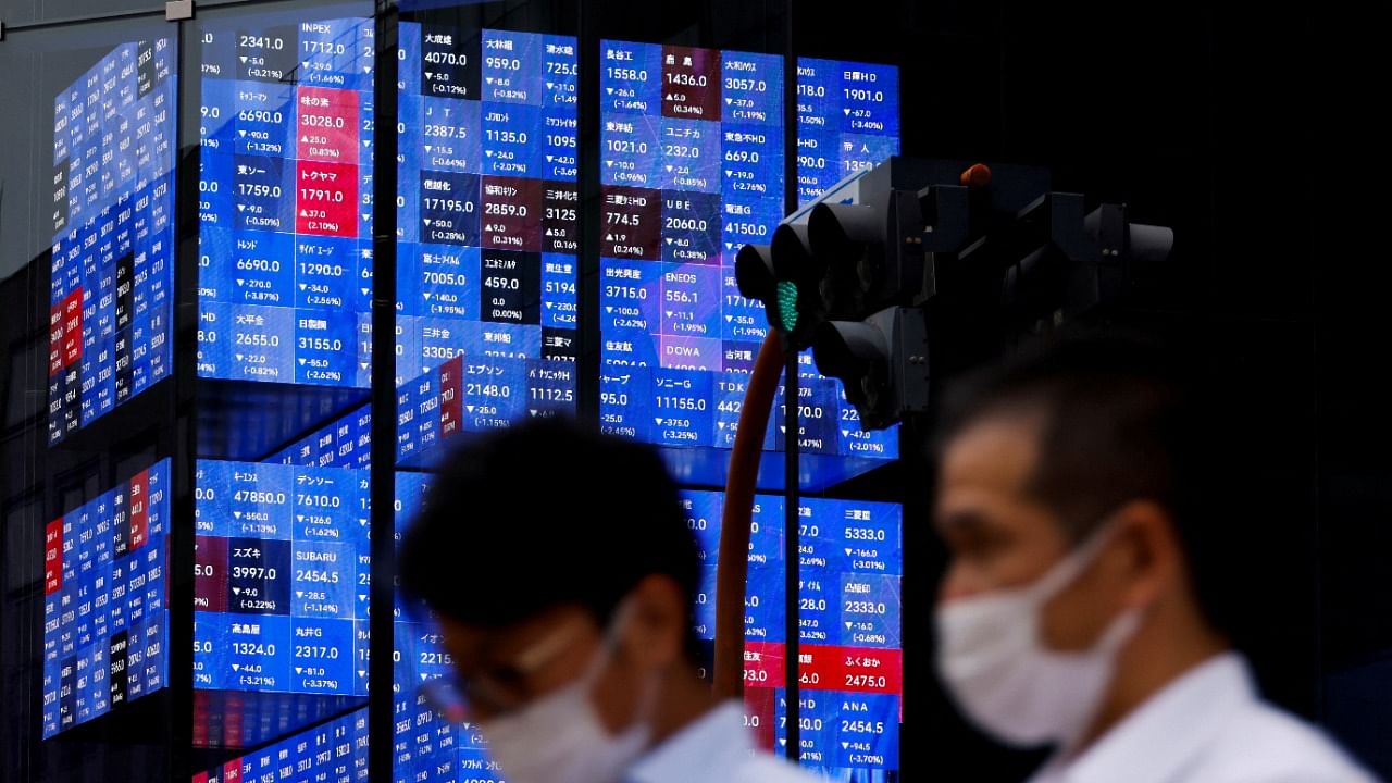 People pass by an electronic screen showing Japan's Nikkei share price index inside a conference hall in Tokyo. Credit: Reuters Photo