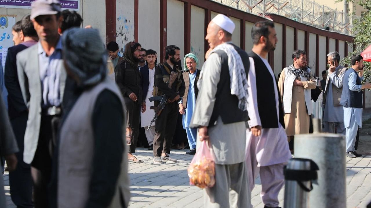 Taliban fighters (C) stand guard as people gather to search for relatives outside a hospital in Kabul on September 30, 2022, following a blast in a learning centre in the Dasht-e-Barchi area of Afghanistan's capital. Credit: AFP Photo