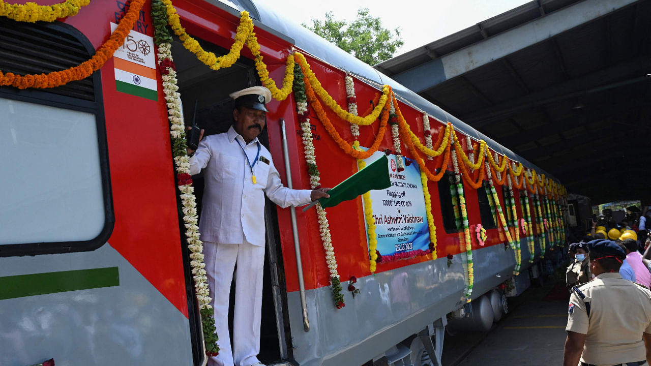 A railway worker waves a flag during a ceremony for the roll-out of 12000th Indian Railways locomotive coach at the Integral Coach Factory in Chennai on May 20, 2022. Credit: AFP File Photo