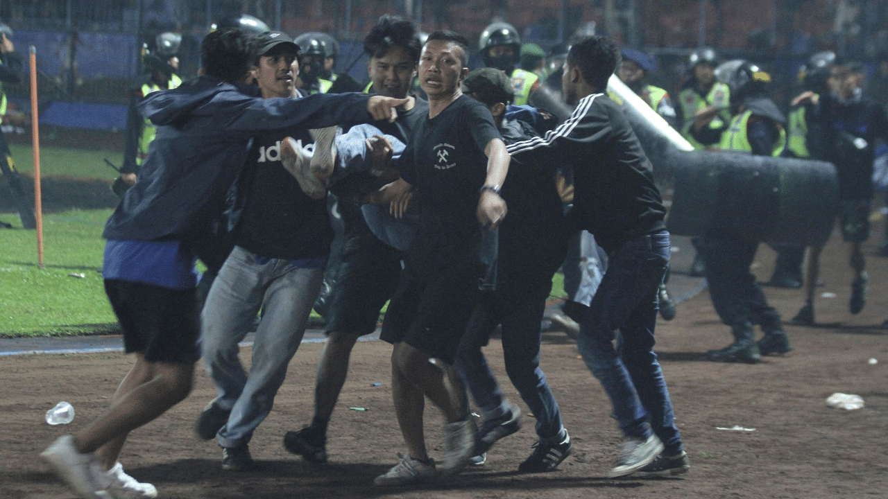 Supporters evacuate a man hit by tear gas fired by police during the riot after the league BRI Liga 1 football match between Arema vs Persebaya, in Malang. Credit: Reuters Photo