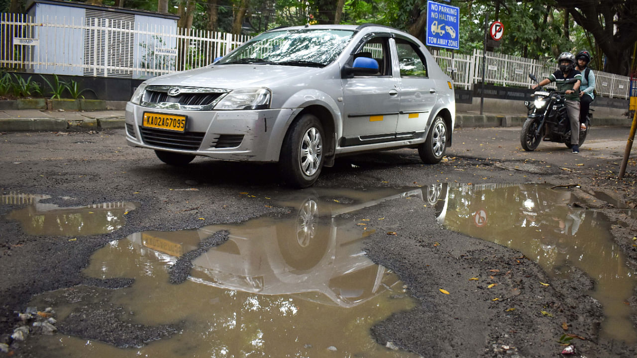 Commuters navigate a pothole ridden-patch of Rest House Road, Bengaluru on Friday, September 30, 2022. Credit: DH Photo