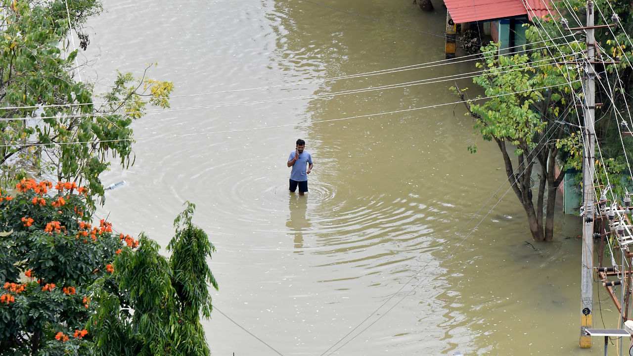 A man speaks on his mobile phone as he wades through a water-logged road in a residential area following torrential rains in Bengaluru, India, September 7, 2022. Credit: Reuters File Photo