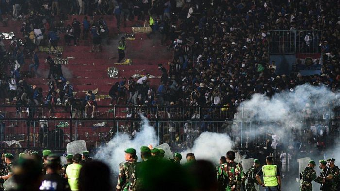 In this picture taken on October 1, 2022, a group of people carry a man at Kanjuruhan stadium in Malang, East Java. Credit: AFP Photo