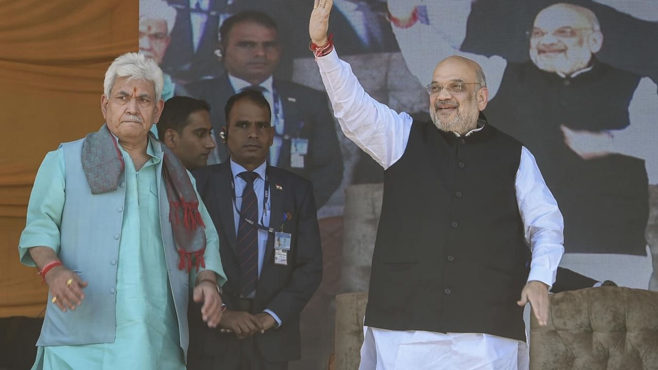 Union Home Minister Amit Shah, with J & K Lt Governor Manoj Sinha, waves at crowd during a public rally at the Showkat Ali Stadium in Baramulla district. Credit: PTI Photo