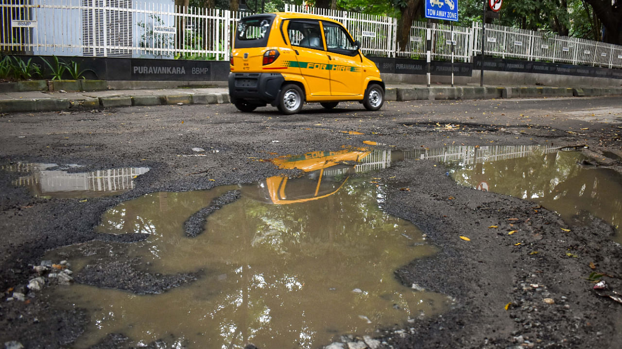 Commuters navigate on a pothole ridden patch of road at Rest House Road, Bengaluru on Friday, September 30, 2022. Credit: DH Photo