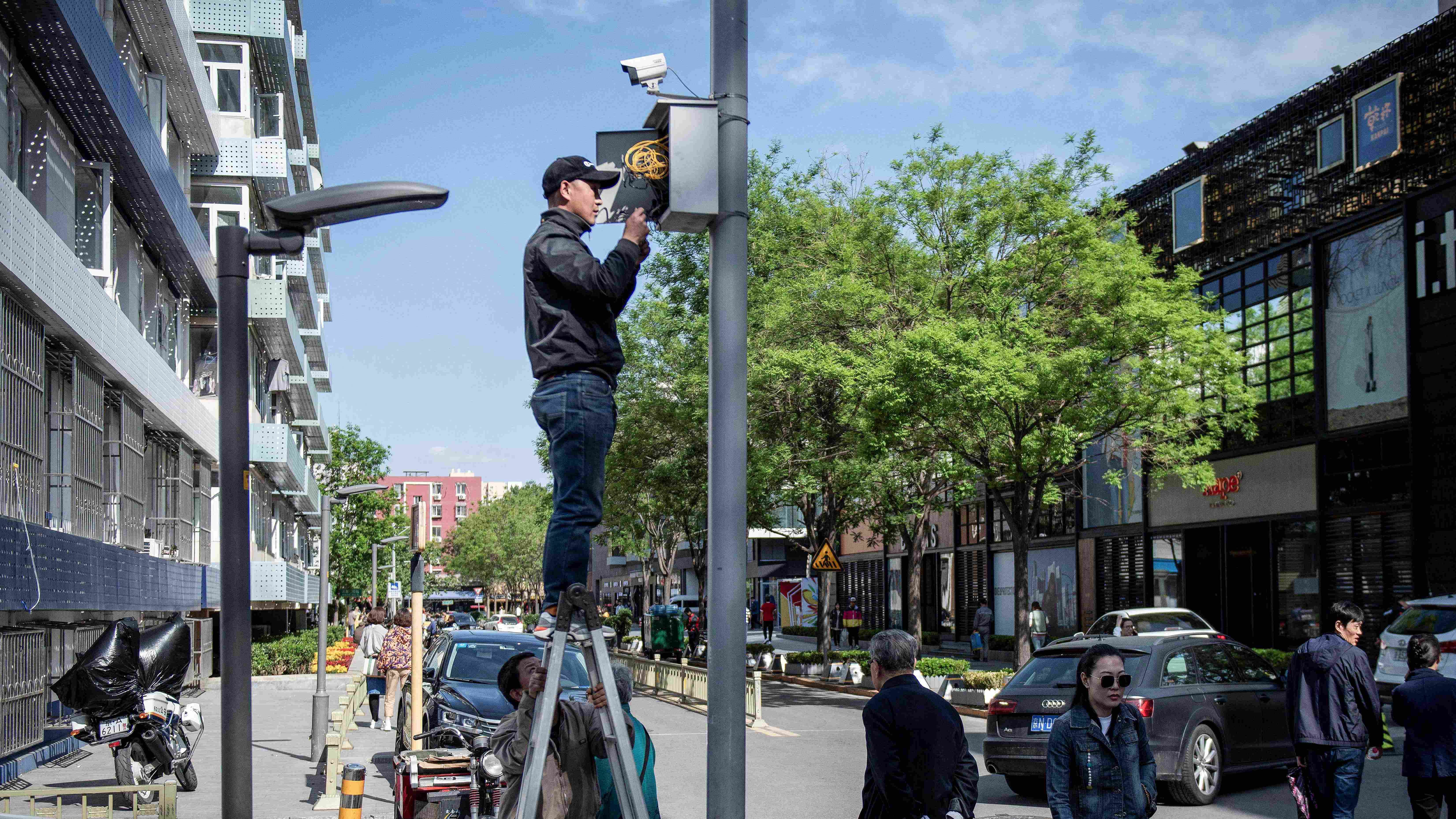 A worker installs a closed circuit television (CCTV) camera along a street in Beijing. Credit: AFP Photo