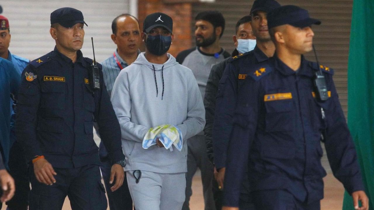 Nepali cricketer Sandeep Lamichhane (C) is escorted by police after being taken into custody to face rape charges, at Tribhuvan international airport in Kathmandu. Credit: AFP Photo