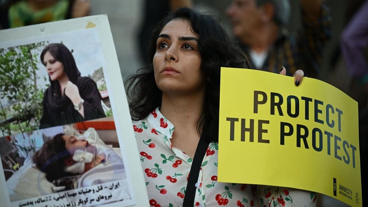 A protester holds pictures of Kurdish Iranian woman Mahsa Amini during a demonstration in solidarity with Iranian women and protestors in Piazza del Campidoglio in Rome on October 5, 2022, following her death in the custody of morality police in Iran. Credit: AFP Photo