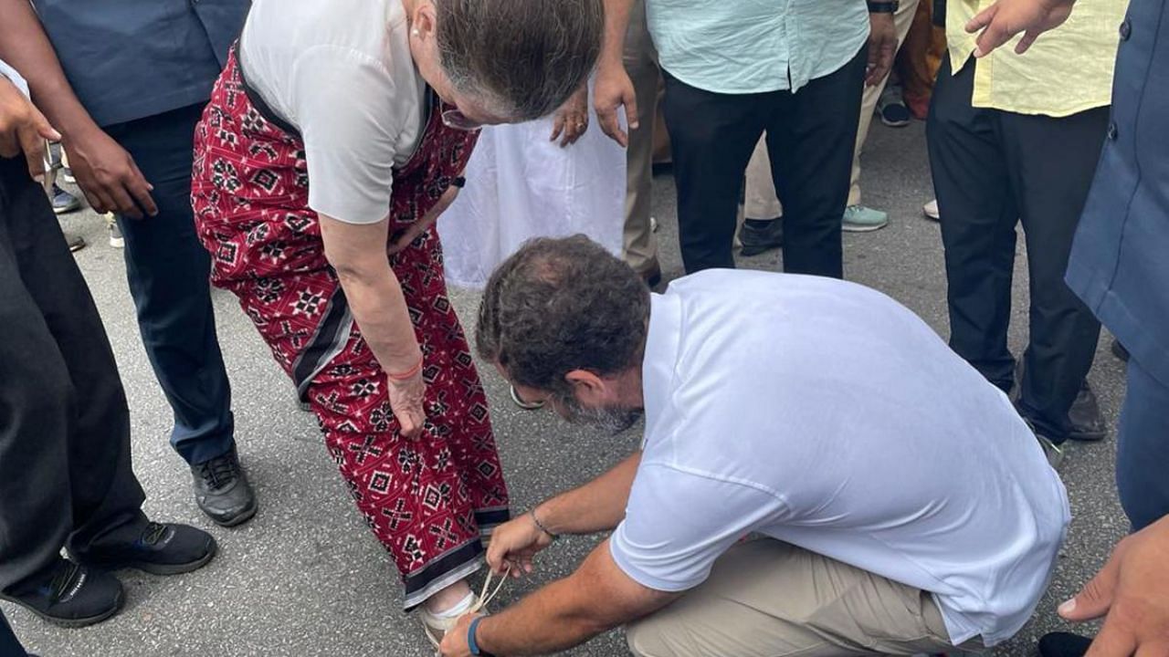 Congress leader Rahul Gandhi ties the shoelaces of his mother and party interim President Sonia Gandhi during the party's 'Bharat Jodo Yatra', in Mandya district. Credit: PTI Photo