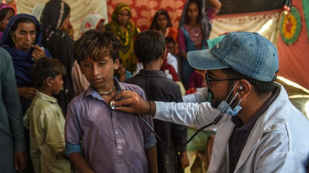 A Pakistani paramedic examines a child at a medical camp set up for internally displaced flood affected peoples in Jamshoro district of Sindh province. Credit: AFP Photo