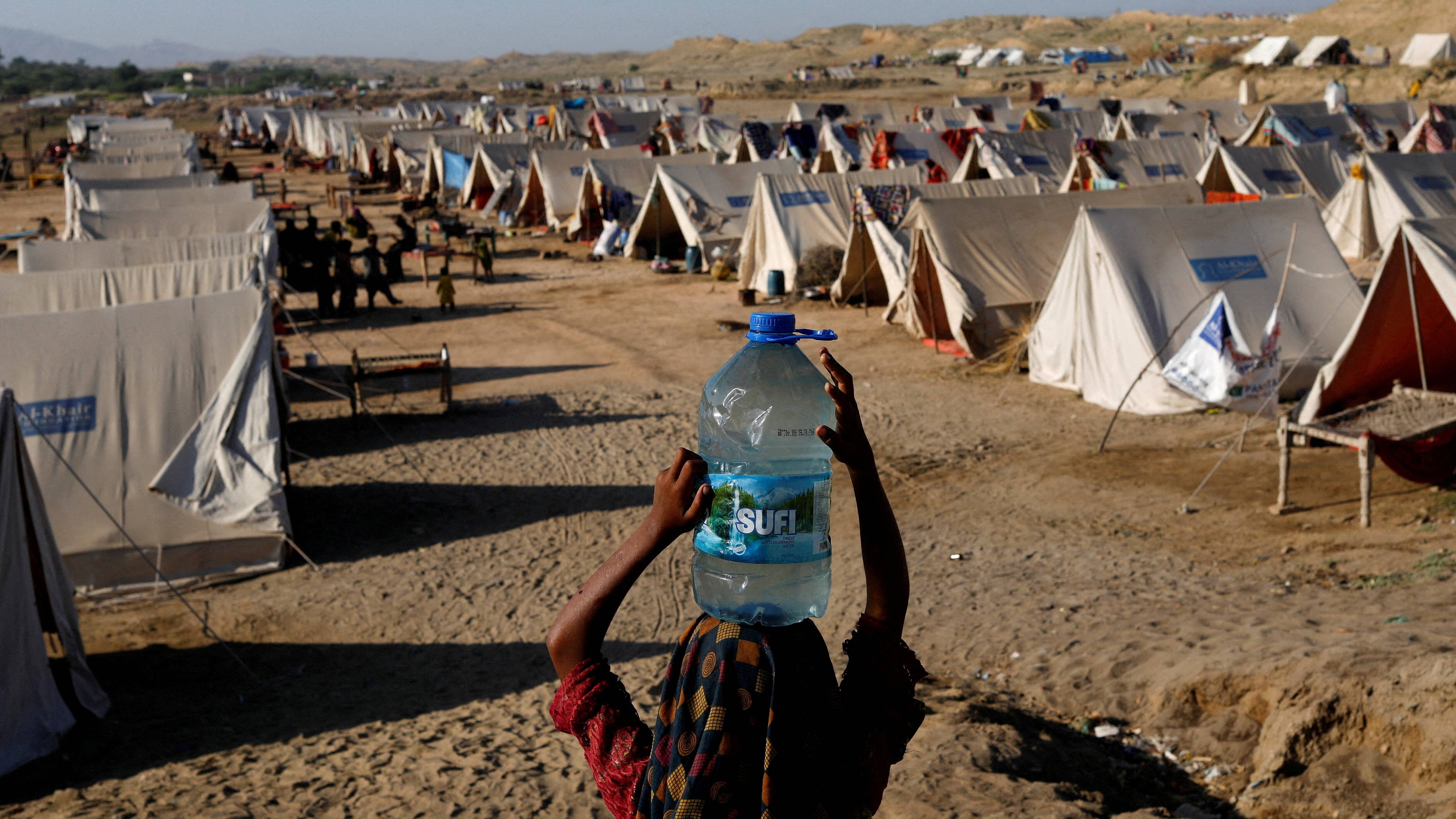  A displaced girl carries a bottle of water she filled from nearby stranded flood-waters, as her family takes refuge in a camp, in Sehwan, Pakistan. Credit: Reuters Photo