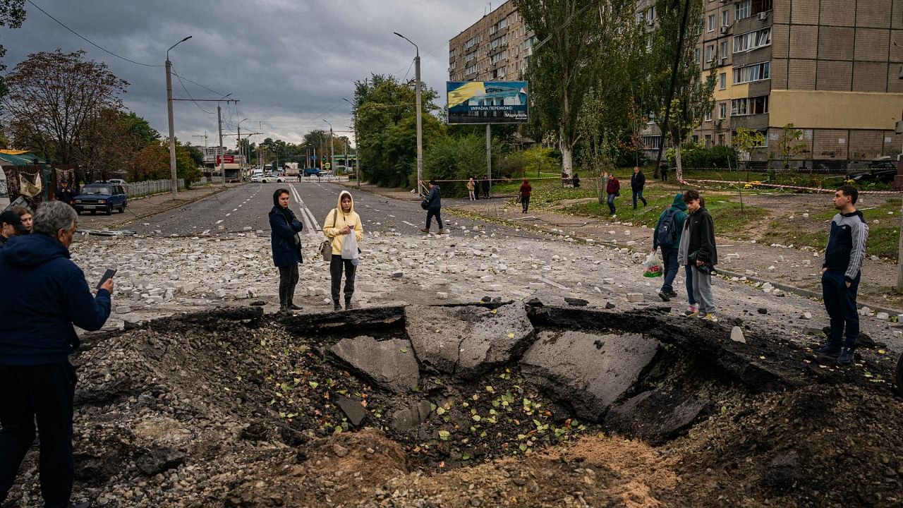 Local residents examine a crater following a missile strike in Dnipro, Ukraine. Credit: AFP Photo