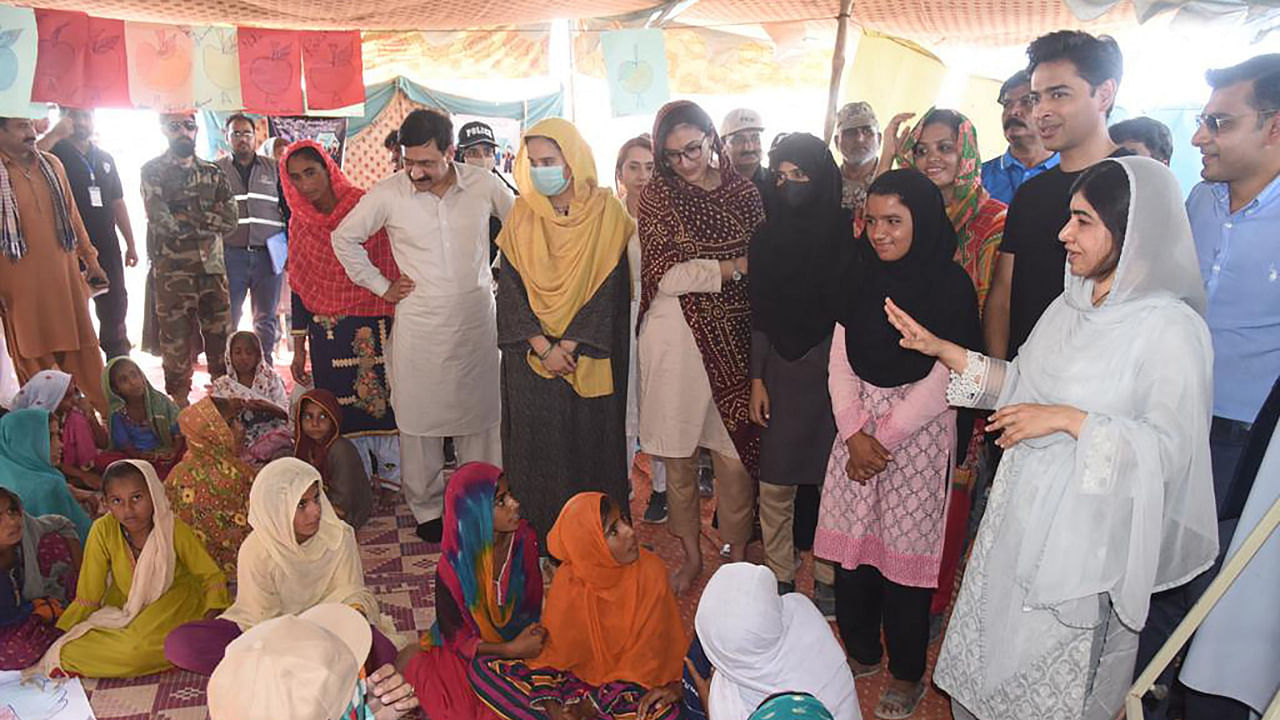 This photo shows Nobel Peace laureate Malala Yousafzai (R) speaking with flood-affected children at a makeshift school in Johi, Dadu district of Sindh province, October 12, 2022. Credit: AFP Photo/Chief Minister House Office of Sindh Province