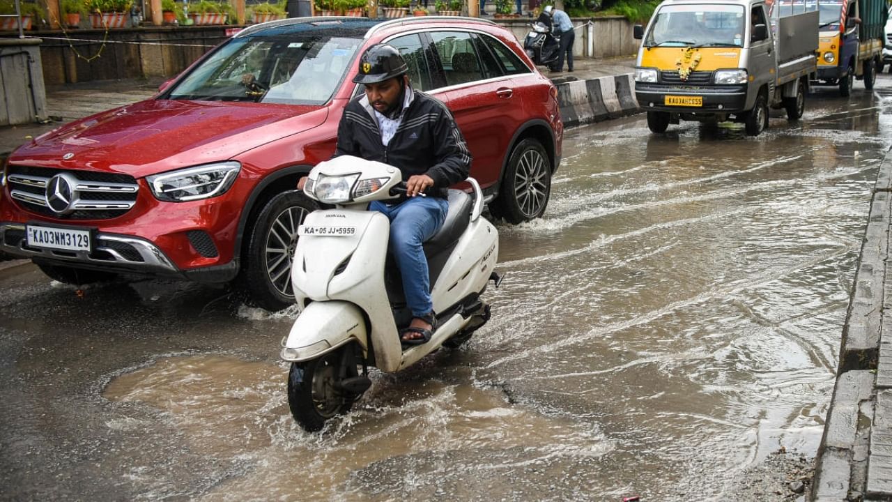 Commuters wade through water logging on Magrath Road, Bengaluru following sudden showers on Thursday, October 13, 2022. Credit: DH Photo/ Pushkar V