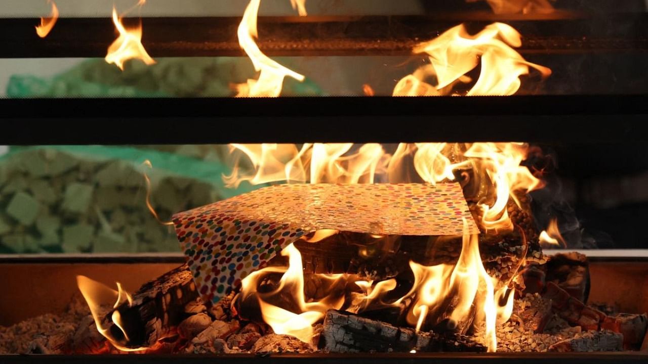 An art piece by British artist Damien Hirst is pictured burning during a photocall at the Newport Street Gallery in London, on October 11, 2022, as part of Hirst's exhibition "The Currency", a project for which the artist will set on fire the paintings after having sold them in digital form NFTs (Non-Fungible Token). Credit: AFP Photo