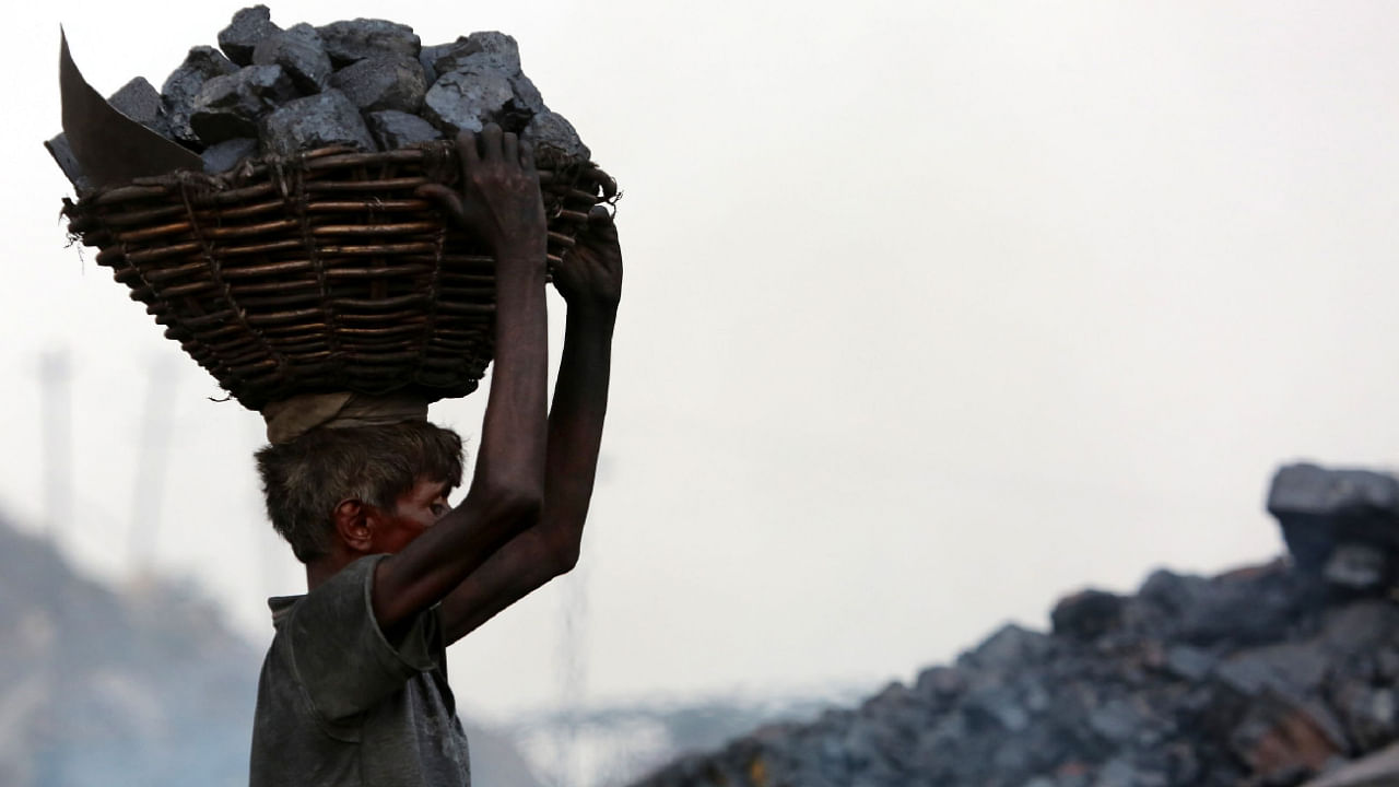 An Indian coal scavenger carries a basket of coal collected at a mine in the district of Dhanbad in Jharkhand. Credit: AFP File Photo