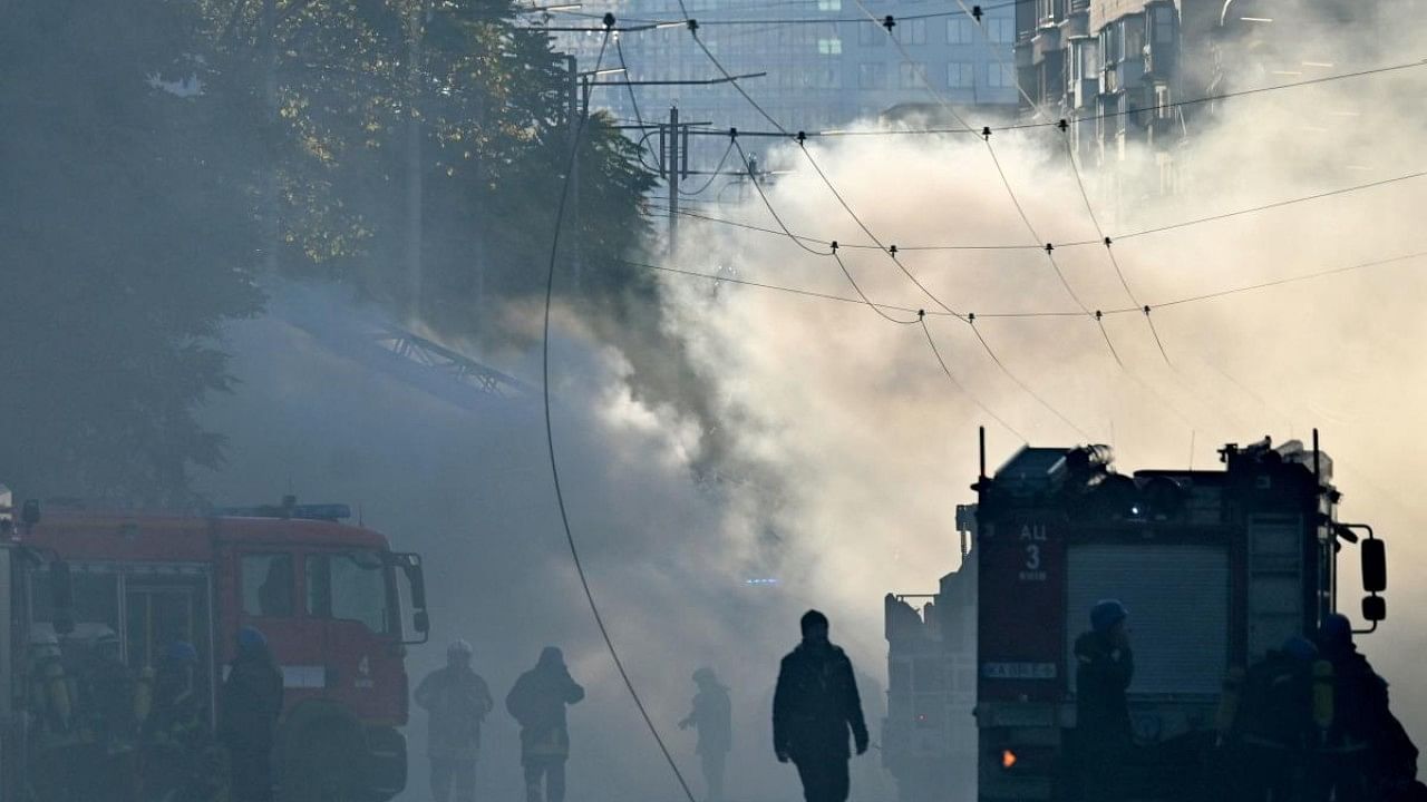 Smoke rises over the street as Ukrainian firefighters prepares, after a drone attack in Kyiv. Credit: AFP Photo