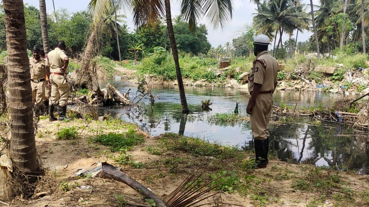 Officials search the area around the rajakaluve near Balagere where the three-year-old boy is suspected to have drowned. Credit: Special Arrangement