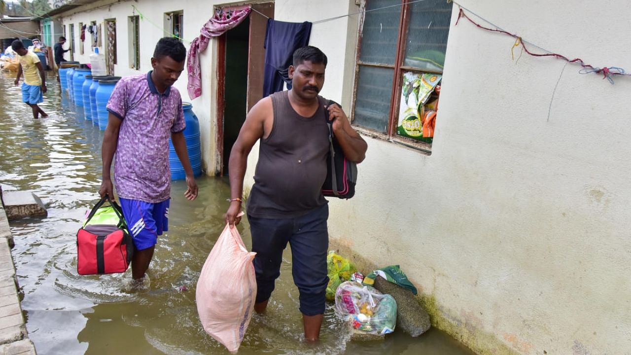Residents move out of their flooded apartment in Bellandur on Thursday. Credit: DH Photo