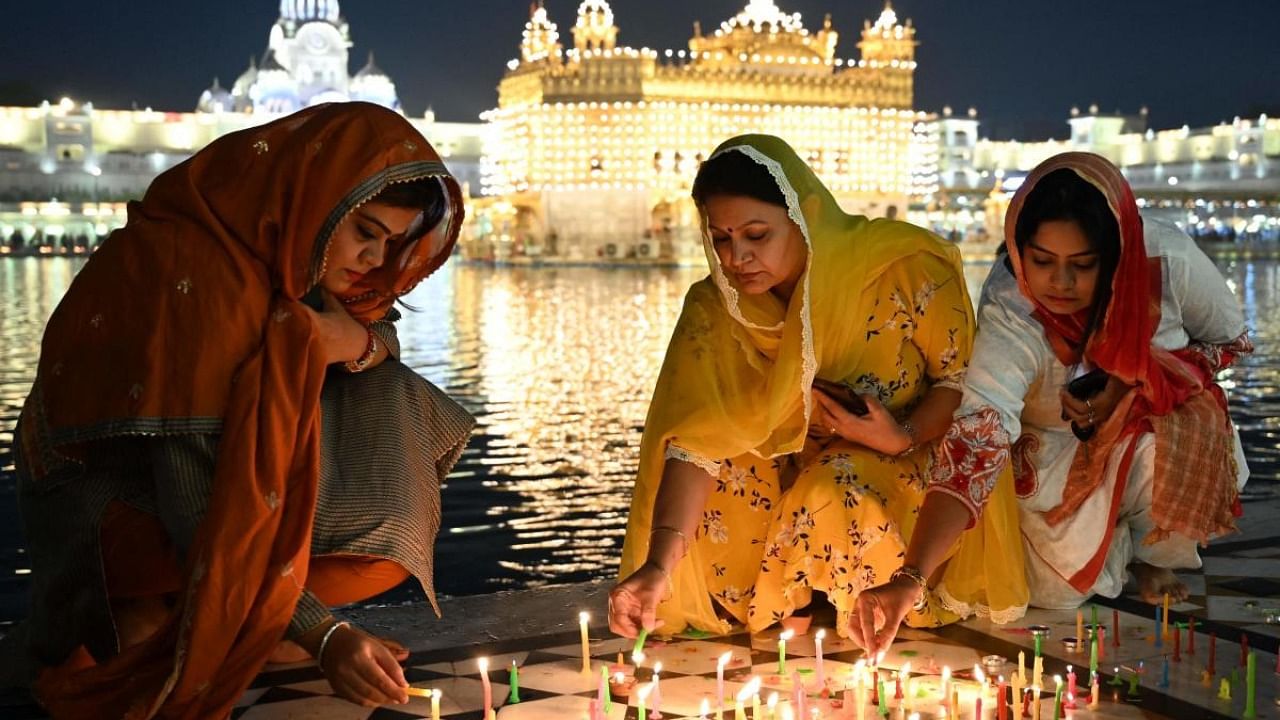 Devotees light candles while paying respect at the illuminated Golden Temple on the occasion of the Bandi Chhor Divas. Representative image. Credit: AFP Photo