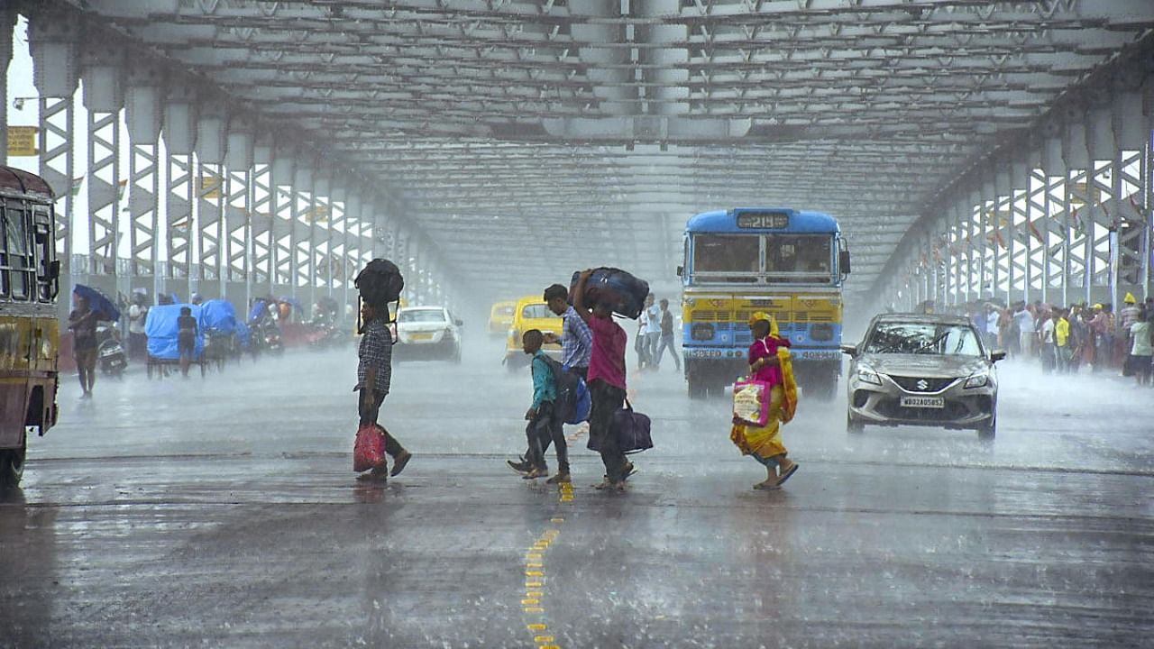 People cross the road on the Howrah Bridge amid monsoon rains in Howrah district in West Bengal. Credit: PTI Photo