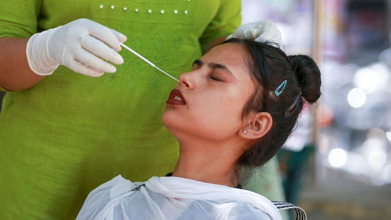 A healthcare worker collects a swab sample of a woman for Covid-19 testing amid a surge in coronavirus cases, in Jammu. PTI File Photo