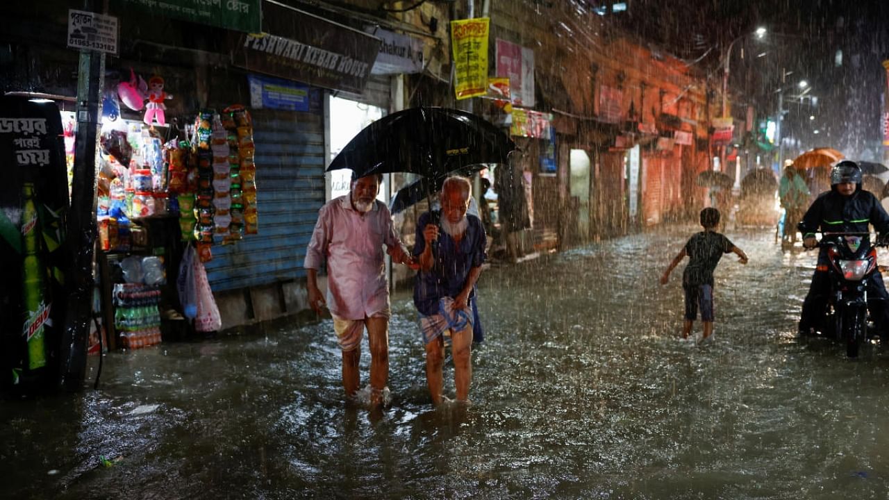 People wade through a flooded street amid continuous rain before the Cyclone Sitrang hits the country in Dhaka. Credit: Reuters Photo