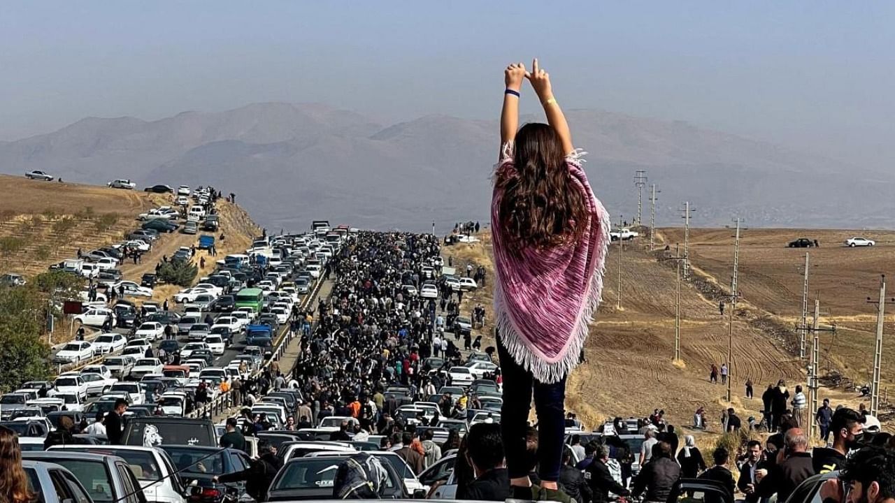 An unveiled woman stands atop a vehicle as thousands make their way towards Aichi cemetery in Saqez in Iran. Credit: AFP Photo