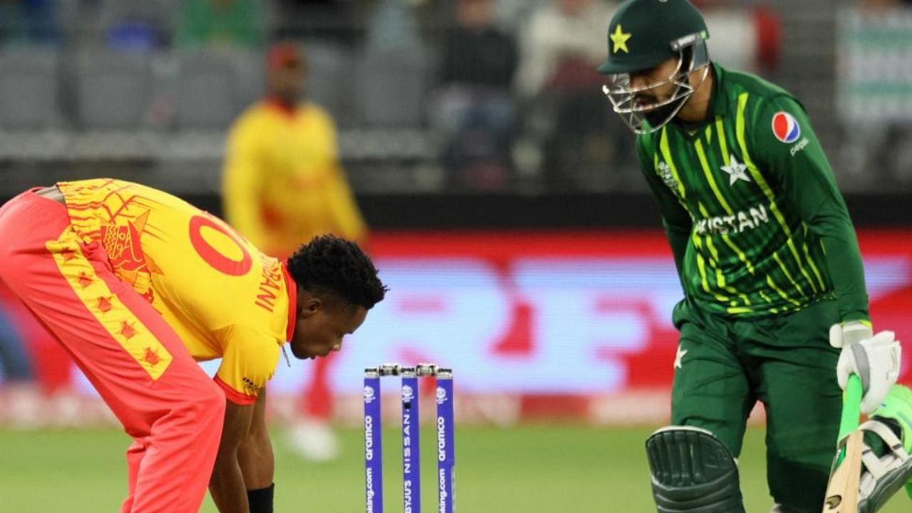 Zimbabwe's Blessing Muzarabani (L) fields the ball as Pakistan's Shadab Khan runs between the wickets during the ICC men’s Twenty20 World Cup 2022 cricket match between Pakistan and Zimbabwe in Perth on October 27, 2022. Credit: AFP Photo