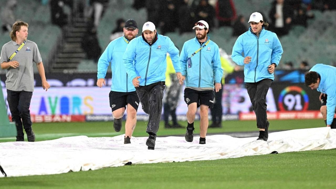 The ground staff runs to cover the pitch area as the ICC men's Twenty20 World Cup 2022 cricket match between Australia and England is being announced abandoned because of rain. Credit: AFP Photo