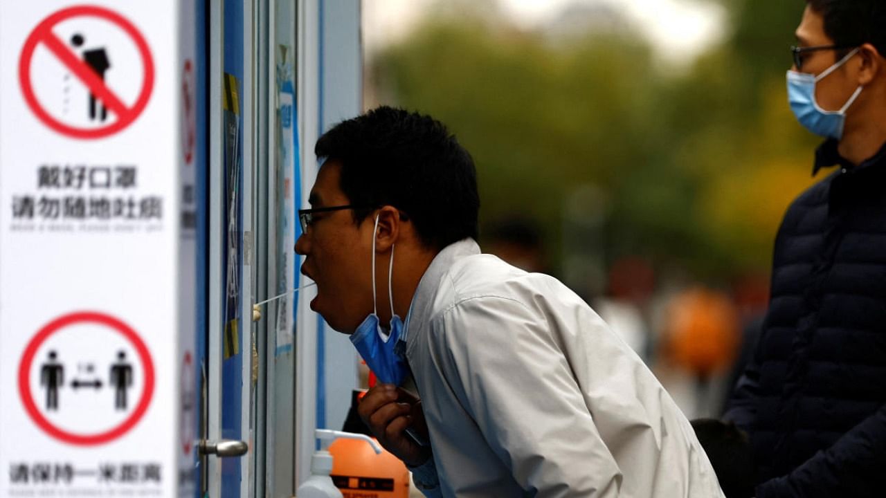 A man has his swab sample taken for Covid test at a testing booth in Beijing, China. Credit: Reuters Photo