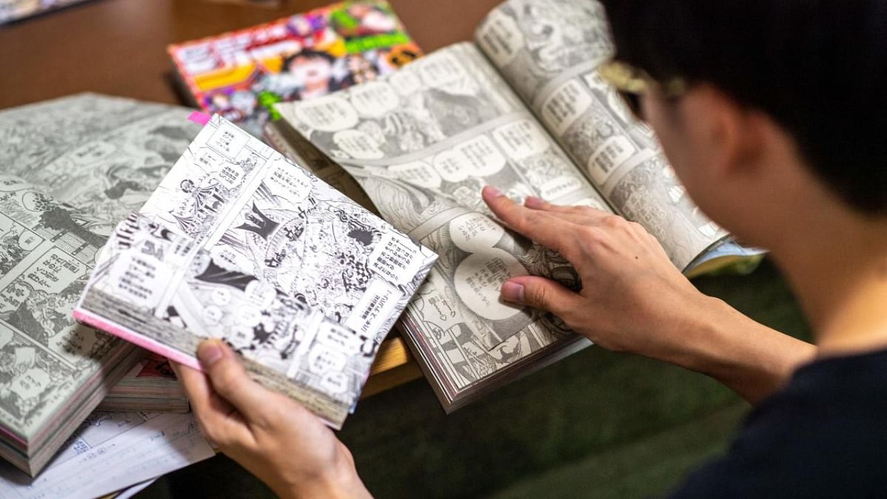 Fan of Japanese manga series 'One Piece' who goes by the online moniker Arimo reads the comic on Weekly Shonen Jump magazine in his home. Credit: AFP Photo