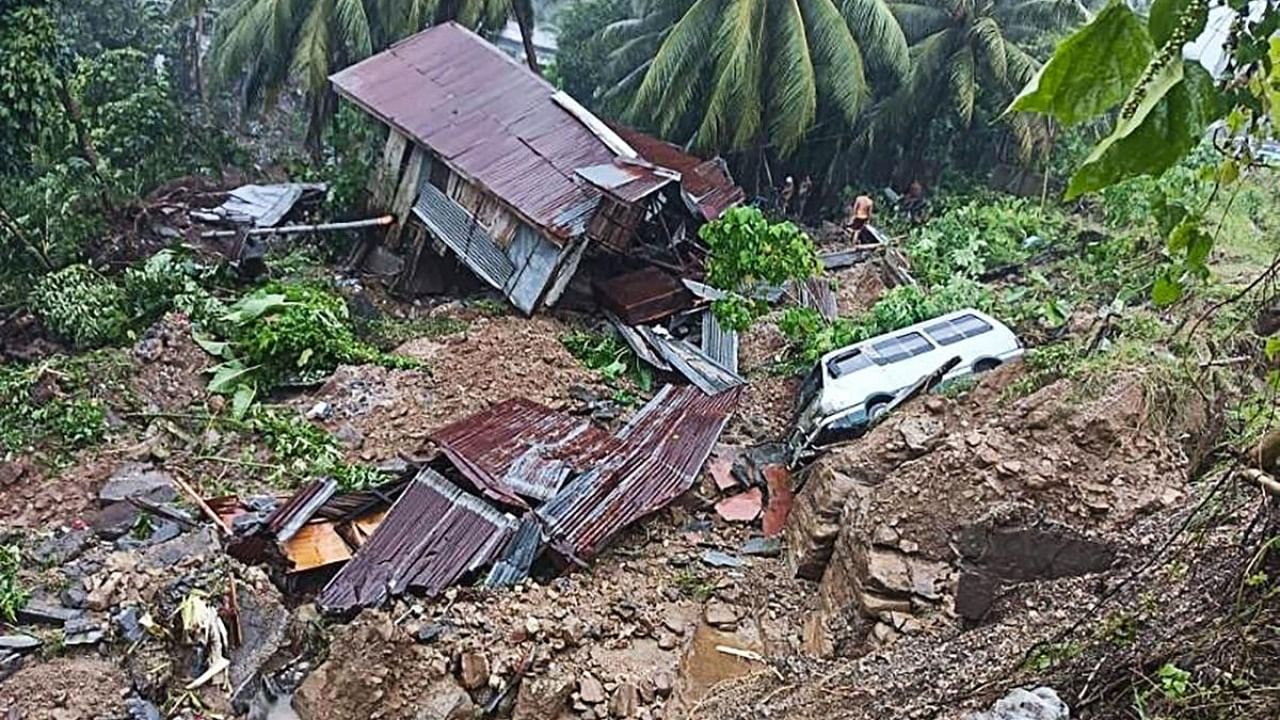 A resident standing next to a damaged house and vehicle after a landslide due to heavy rains in Parang town. Credit: AFP Photo