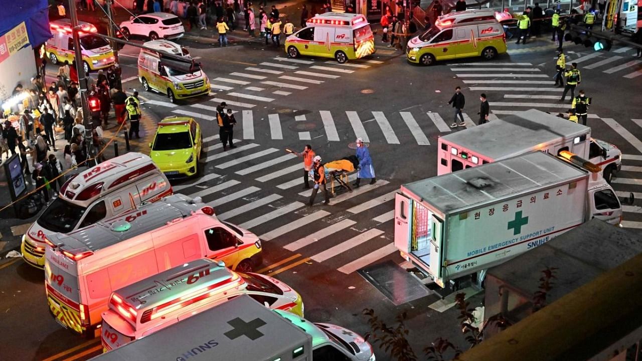 A person, believed to have suffered cardiac arrest, is transported in a stretcher in the popular nightlife district of Itaewon in Seoul. Credit: AFP Photo