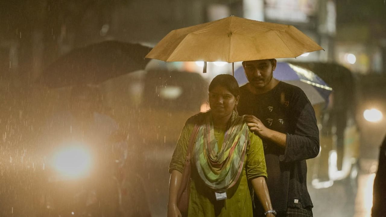Commuters walk during rain due to northeast monsoon rainfall, in Chennai, Monday, Oct. 31. Credit: PTI Photo